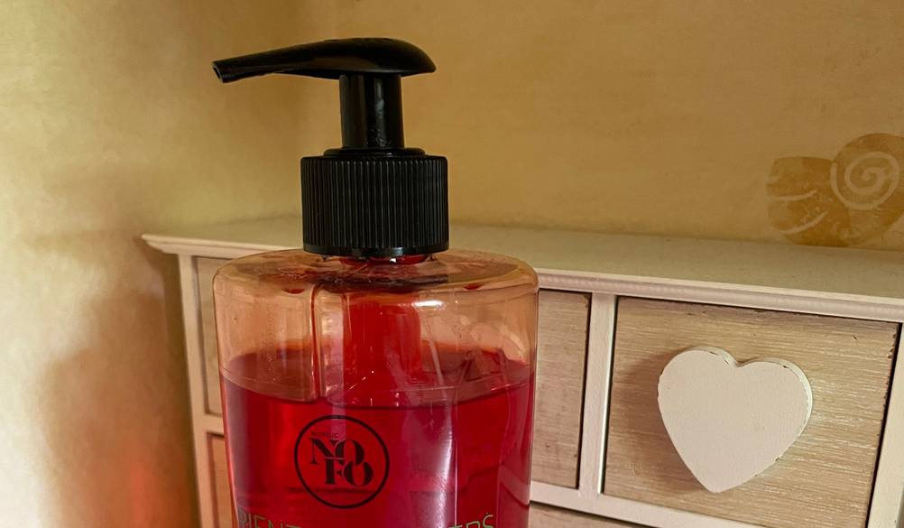 Nahaufnahme des Pumpspenders an einer Flasche der getesteten Seife vor einem Holzkästchen.