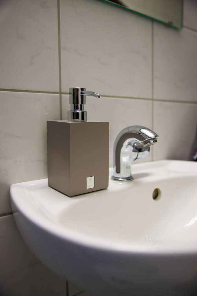 Seifenspender-grau-Test: Seifenspender steht neben einem Wasserhahn.