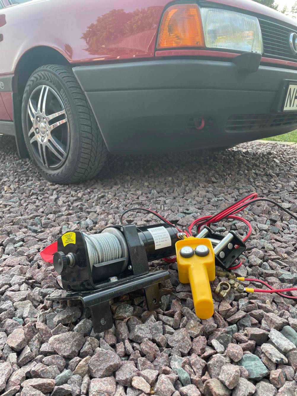 Im Test: Eine Seilwinde 12 V auf einer Steinfläche vor einem Auto.