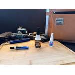 Drei Sekundenkleber stehen nebeneinander vor Werkzeug auf einem Holzbrett