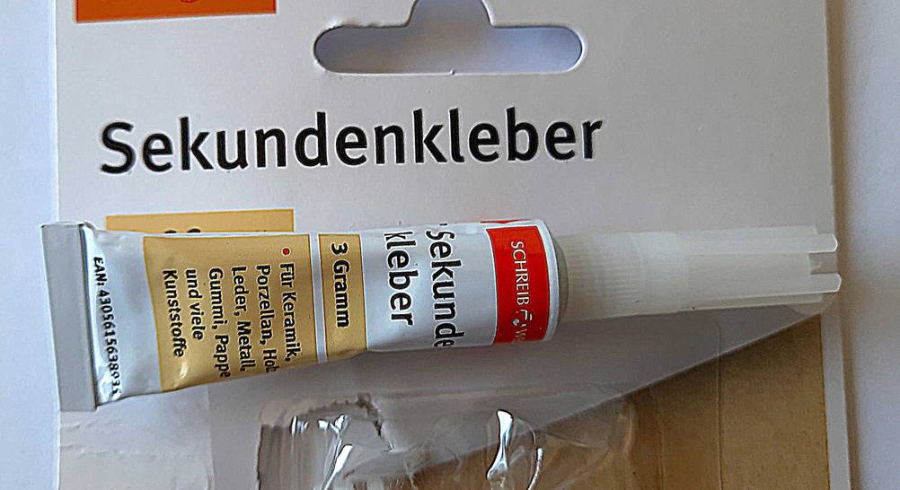 Eine Tube des Sekundenkleber im Test auf seiner Verpackung liegend.
