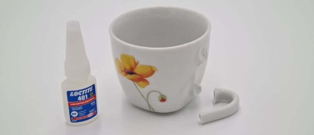 Loctite-Sekundenkleber steht neben einer Tasse mit abgebrochenen Henkel.