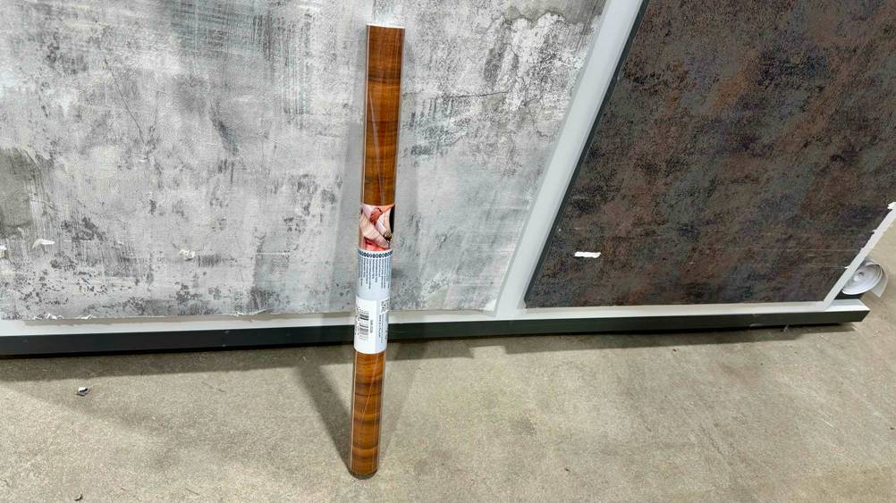 Selbstklebende Tapete getestet: Eine Rolle lehnt an einer Wand.