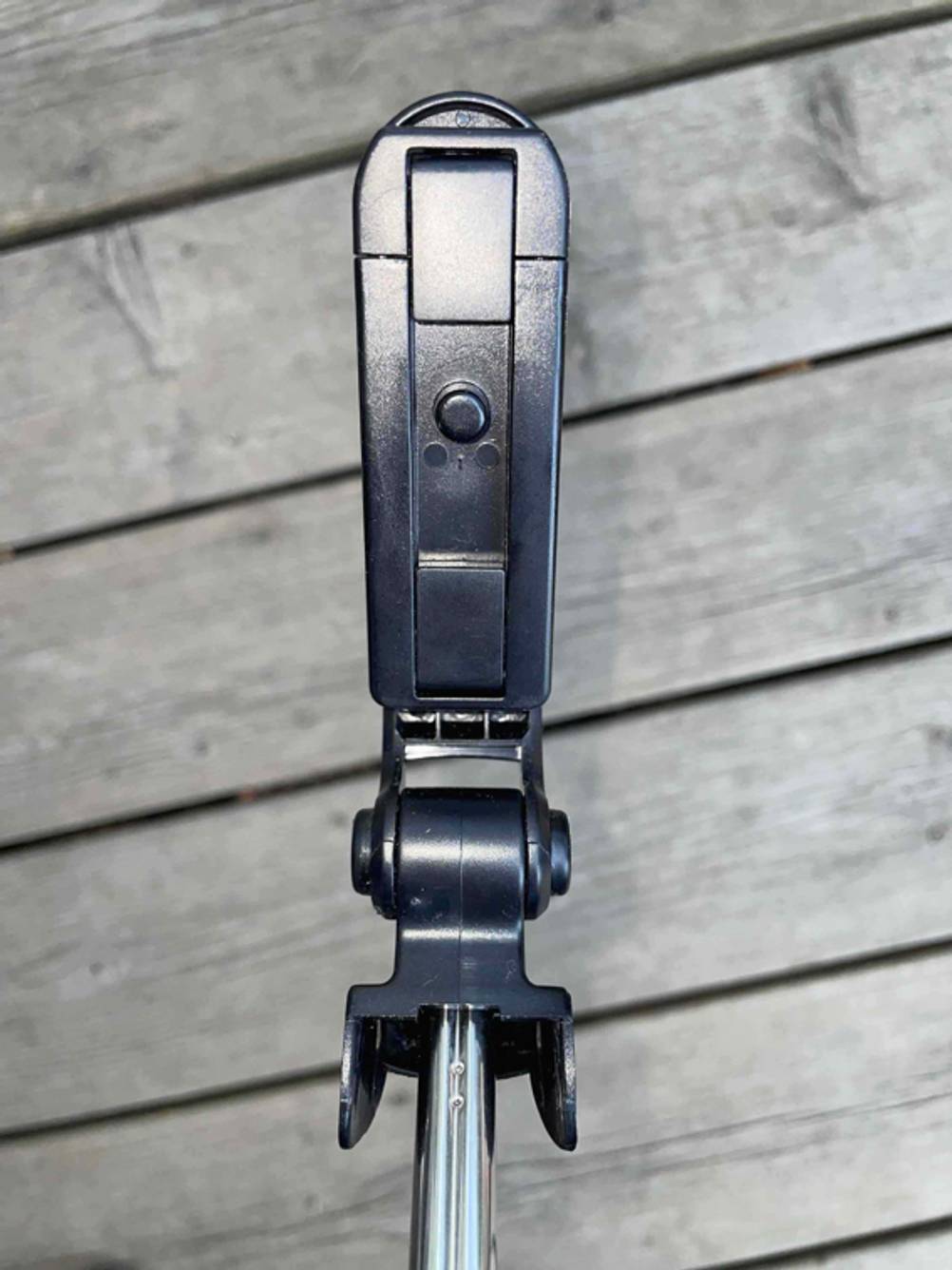 Nahaufnahme der Halterung für das Handy eines getesteten Selfie-Sticks vor einer Holzfläche.
