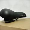 Der Selle Royal 85650 Lagoon ist in Seitenansicht auf einem Karton platziert. Die runde Form der Sitzfläche ist gut sichtbar.
