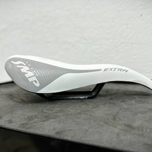 Der Selle SMP Extra Color Edition ist seitlich auf einem Tisch positioniert. Der markante Bogen des Sattels ist gut sichtbar.