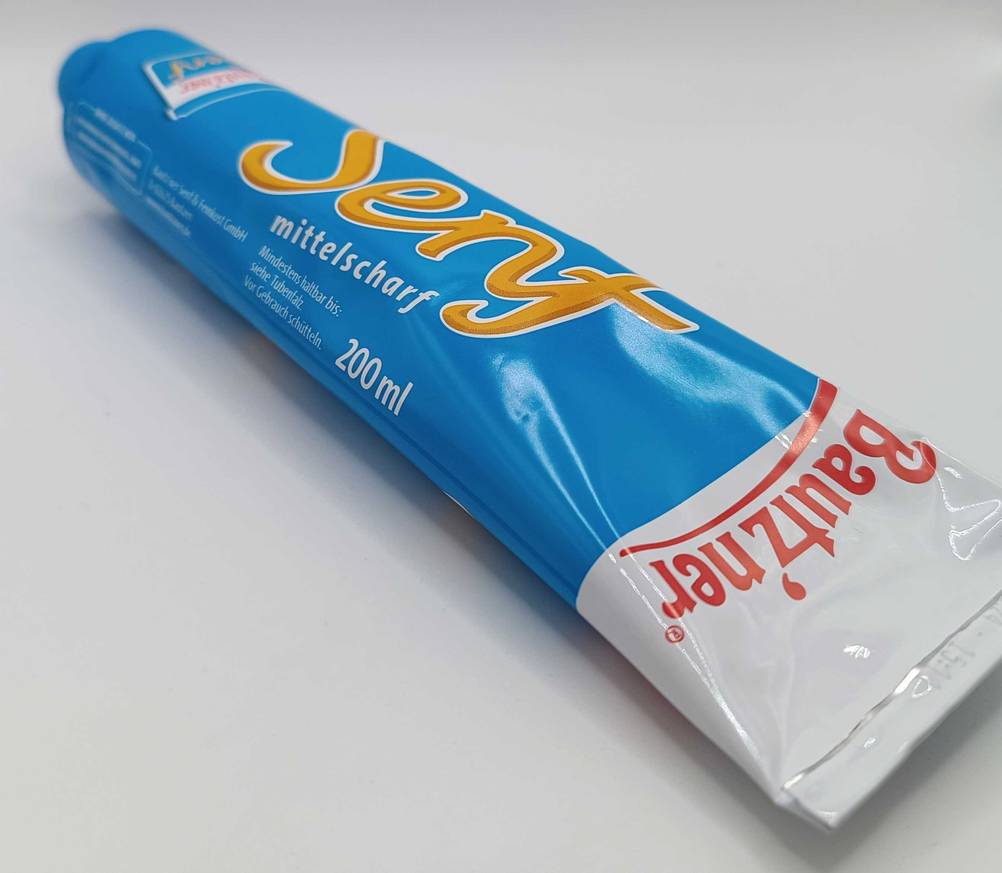 Senf getestet: Nahaufnahme des Logos einer Tube auf hellen Untergrund.