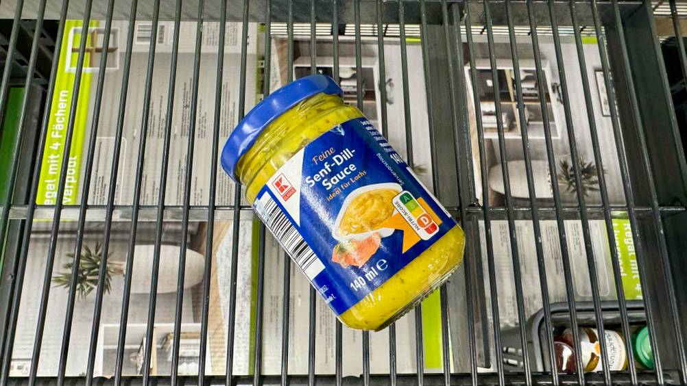 Ein Glas der getesteten Senf-Dill-Sauce auf eine Gitter liegend.