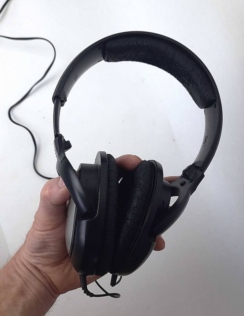 Eine Hand hält den getesteten Sennheiser-Kopfhörer mit Kabel vor einem weißen Hintergrund.
