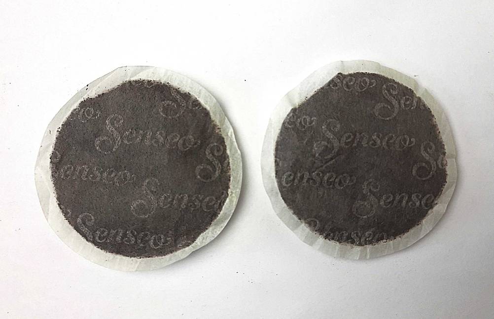 Zwei Senseo-Pads im Test auf einer hellen Fläche.