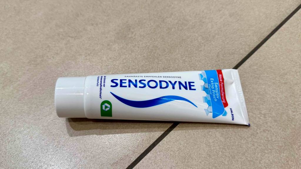 Eine Tube getestete Sensodyne-Zahnpasta liegt auf Fliesen.