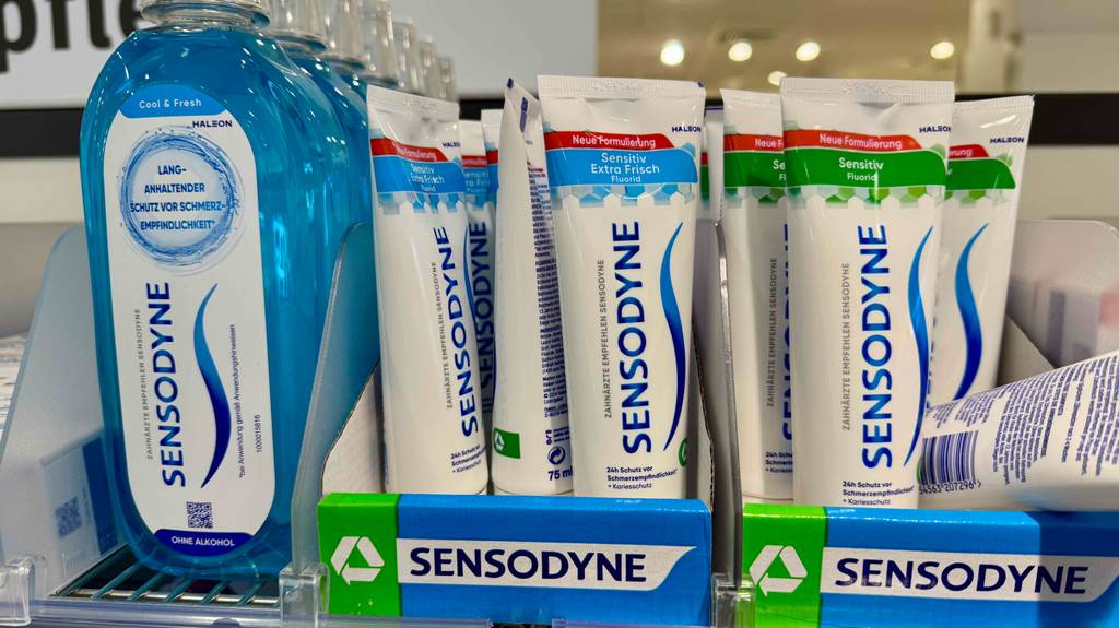 Sensodyne-Zahnpasta im Test: Mehrere Tuben mit unterschiedlichen Varianten stehen neben- und hintereinander zusammen mit anderen Sensodyne-Produkten in einem Regal.