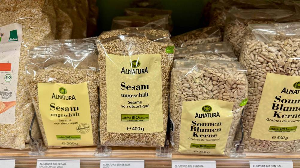 Mehrere Packungen des getesteten Sesams in einem Regal neben anderen Produkten.