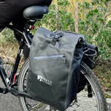 Die SevenRivers Fahrradtasche ist am hinteren Gepäckträger eines Fahrrads montiert. Eine Person fährt das Fahrrad mit montierter Tasche.