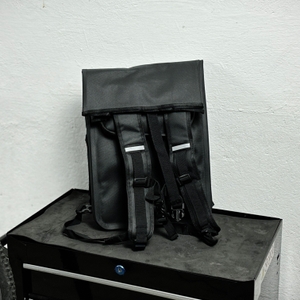 Die Rückseite der Sevenrivers-Fahrradtasche zeigt zwei Rucksackträger mit Reflektorstreifen. Die Tasche steht frei auf einem Werkzeugschrank.