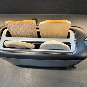 In den Spalten des Severin AT 2509 stehen vor dem Toasten ein Vollkorntoast, ein Weizentoast und ein geschnittenes Brötchen.