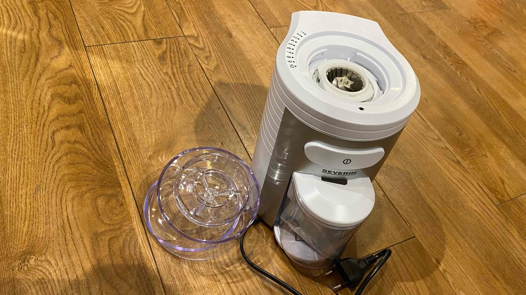Im Test: eine Kaffeemühle von Severin steht mit nebenliegendem Deckel auf einer Holzfläche.