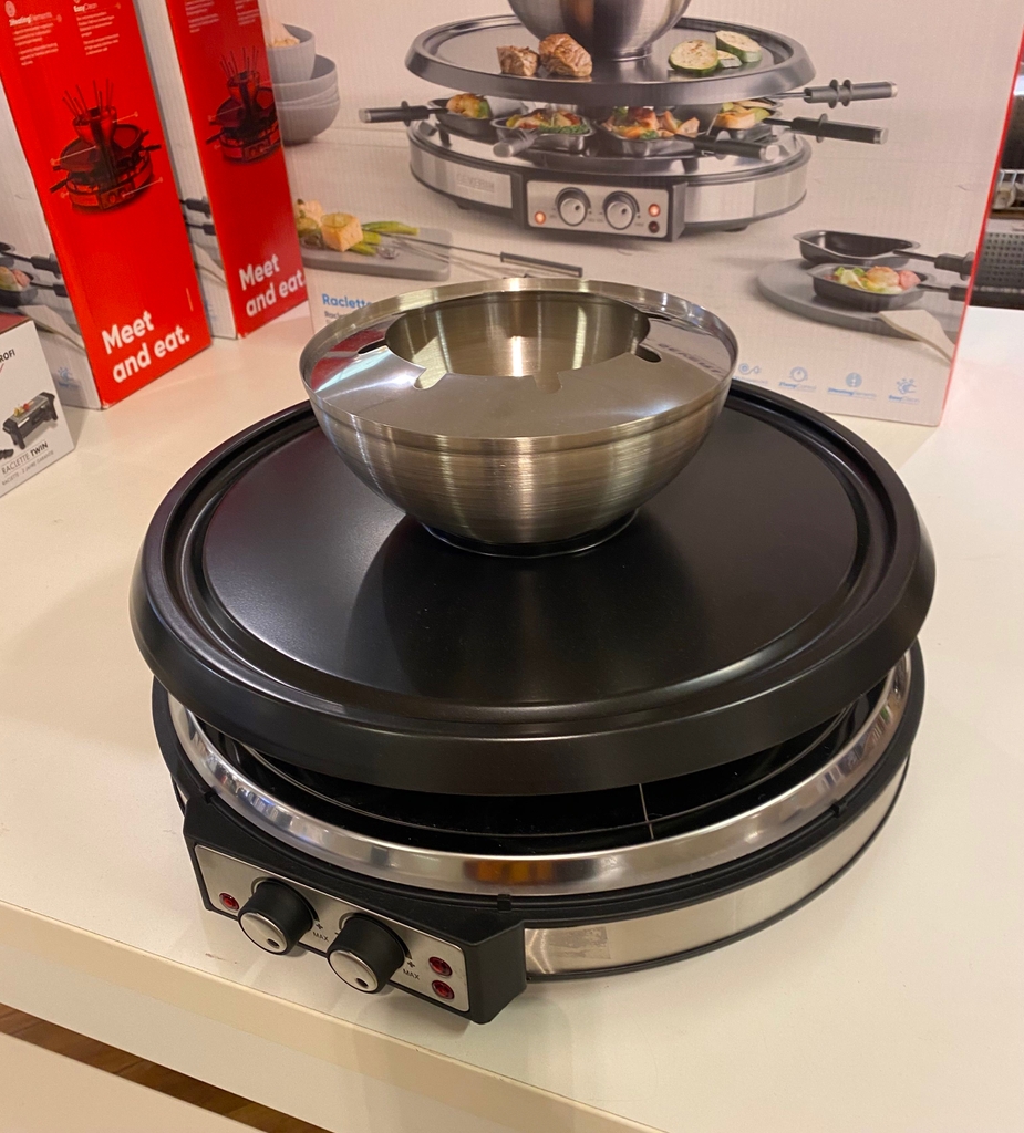 Raclette im Test: Ein aufgebautes Gerät steht vor einem Karton auf weißer Fläche mit Fondue-Aufsatz.