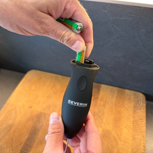 Eine Hand legt eine Batterie in den Severin SM 3590