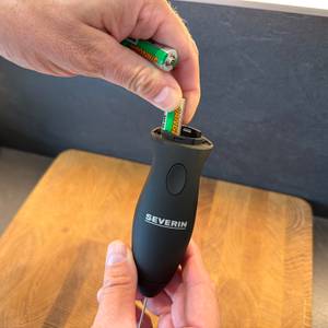 Eine Hand legt eine Batterie in den Severin SM 3590