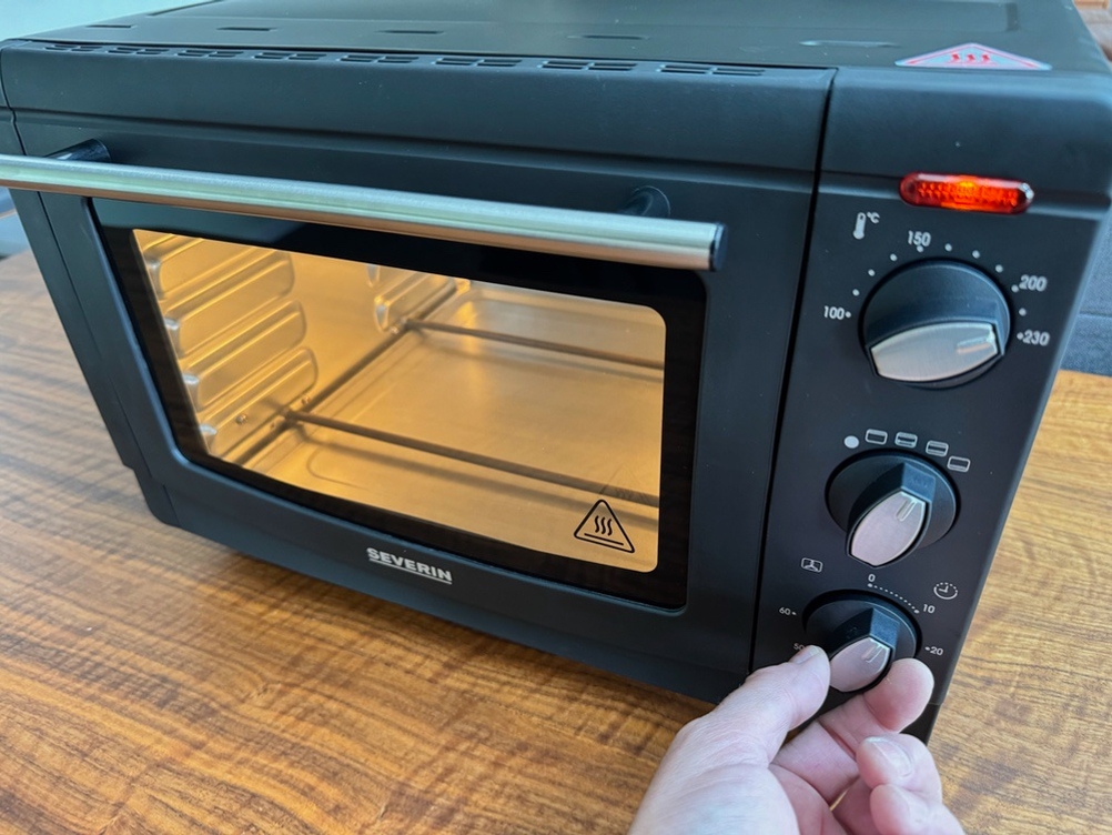 Eine Hand stellt etwas an einem Drehregler des Severin TO 2068 ein