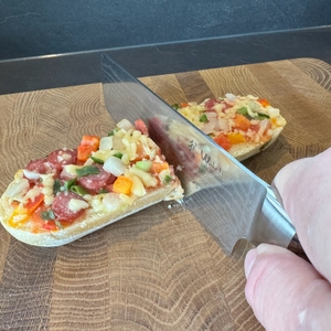 Mit einem Messer wird ein Salamibaguette geschnitten