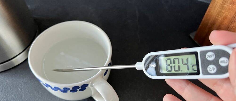 80,4 Grad Celsius auf Temperaturmesser, der in eine Tasse gehalten wird