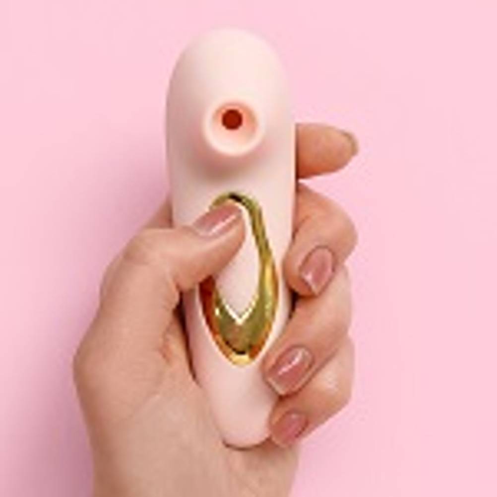 Sexspielzeug getestet: Rosa-goldener Stoßwellenvibrator auf rosa Untergrund