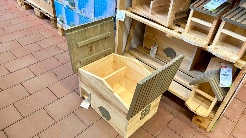 Ein getestetes Igelhaus steht mit geöffnetem Dach auf Steinfliesen.