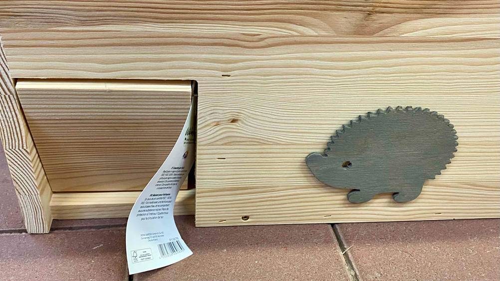 Igelhaus im Test: Detailansicht der Klappentür, nebendran ist ein Holzigel aufgebracht.