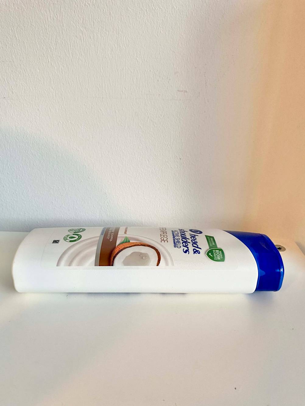 Shampoos gegen Schuppenflechte im Test: Eine Flasche von der Seite auf einer hellen Fläche liegend.