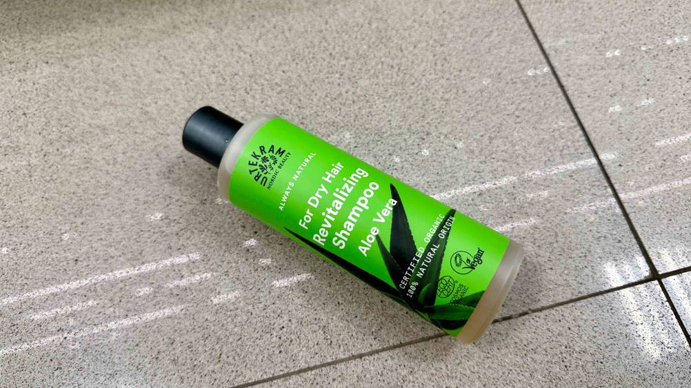 Eine Flasche des getesteten Shampoos für trockenes Haar liegt auf einem Fließenboden.