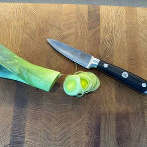 Ein wenig geschnittener Porree liegt neben dem Shan-Zu-Gemüsemesser