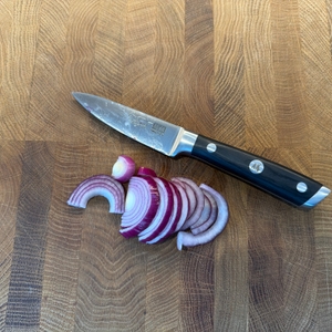 Eine geschnittene Zwiebel liegt neben dem Shan-Zu-Gemüsemesser