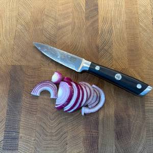 Eine geschnittene Zwiebel liegt neben dem Shan-Zu-Gemüsemesser