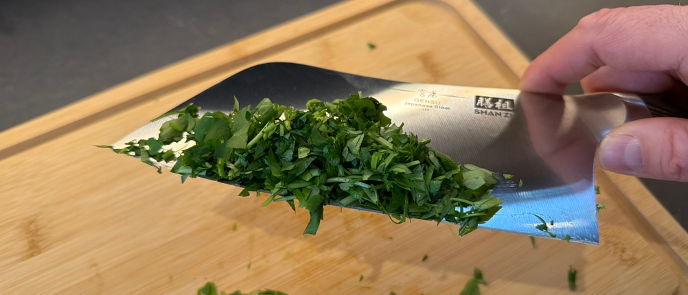 Zerkleinerte Petersilie hängt am Shan-Zu-Hackmesser