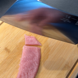 Das Shan-Zu-Hackmesser wird über zwei zerschnittene Stücke Fleisch gehalten