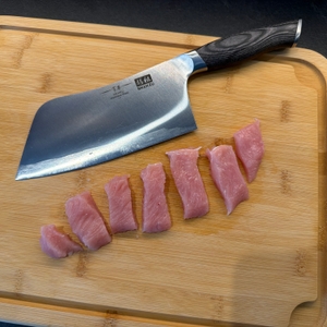 Zerschnittene Stücke Fleisch liegen neben dem Shan-Zu-Hackmesser