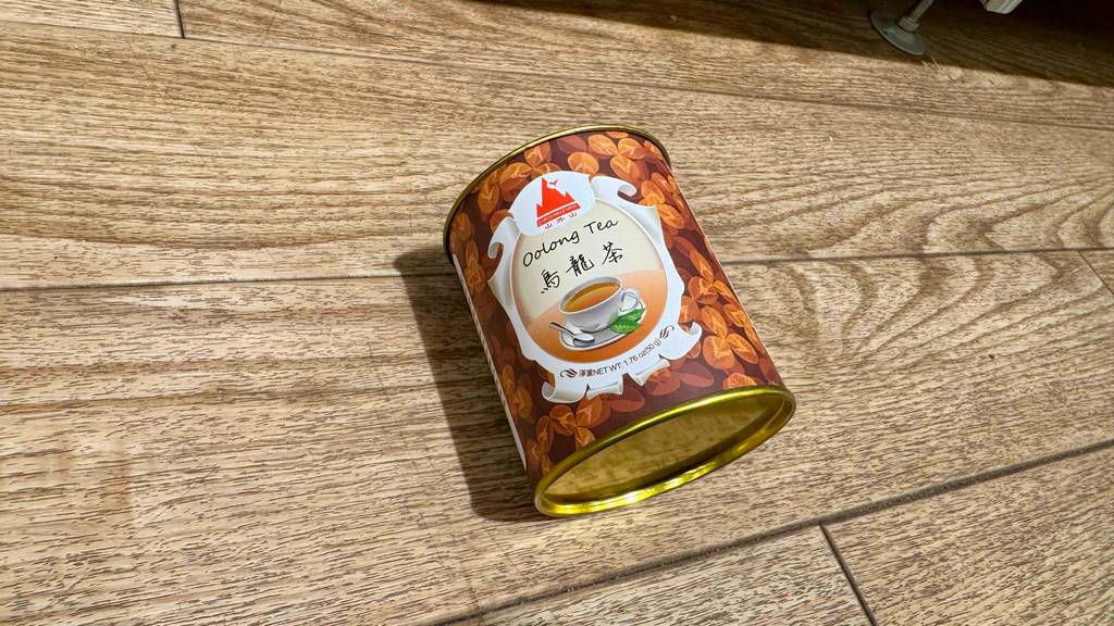 Eine Dose getesteter Oolong-Tee liegt mit Blick auf die Unterseite auf einem Boden.