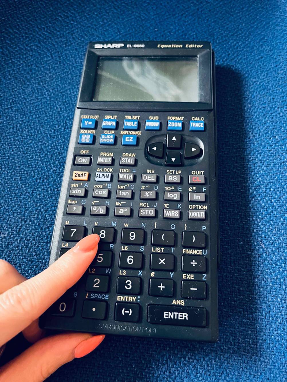 Ein Finger tippt auf die Zahlen eines getesteten grafischen Taschenrechners