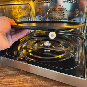 Eine Hand legt den Drehteller in die Sharp R843INW