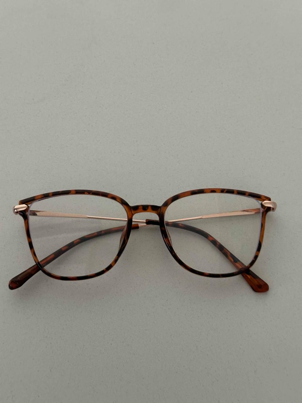 Eine geschlossene, getestete Blaulichtfilter-Brille mit Vollrahmen im Horn-Design liegt auf einer grauen Oberfläche.