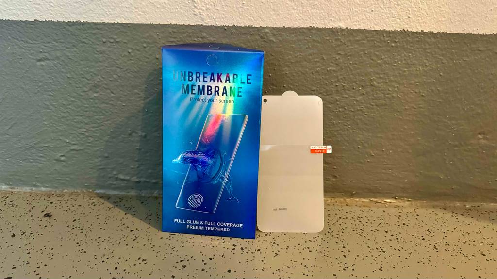 Eine blaue Verpackung inklusive eines getesteten Samsung-Galaxy-S10-Panzerglases steht an der braunen Wand.
