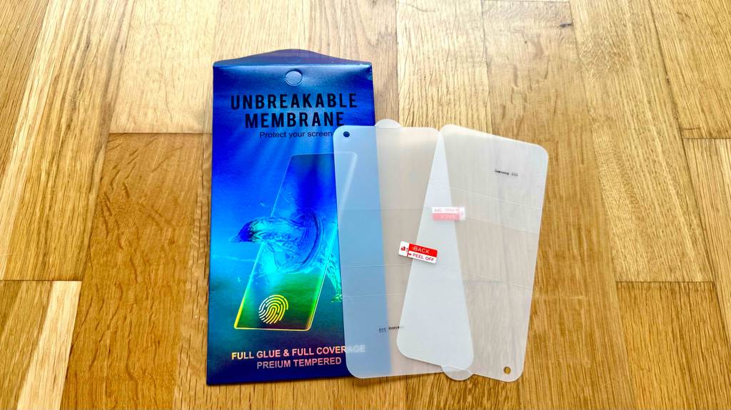 Eine blaue Verpackung mit einem Samsung-Galaxy-S10-Panzerglas im Test liegt auf einem Holzboden.