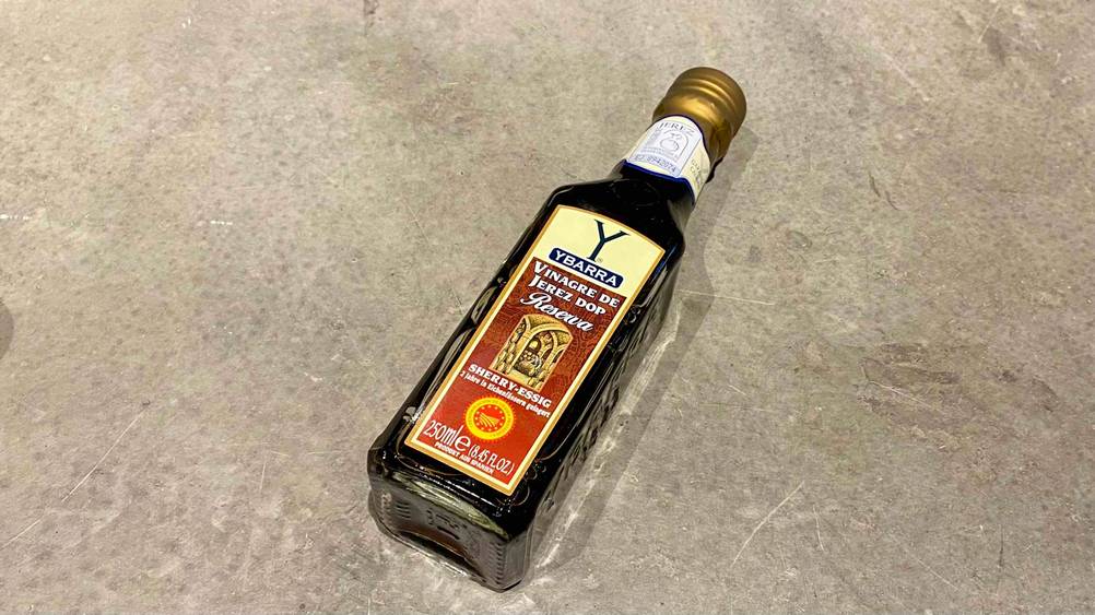 Eine Flasche des getesteten Sherryessigs auf einem Betonboden.