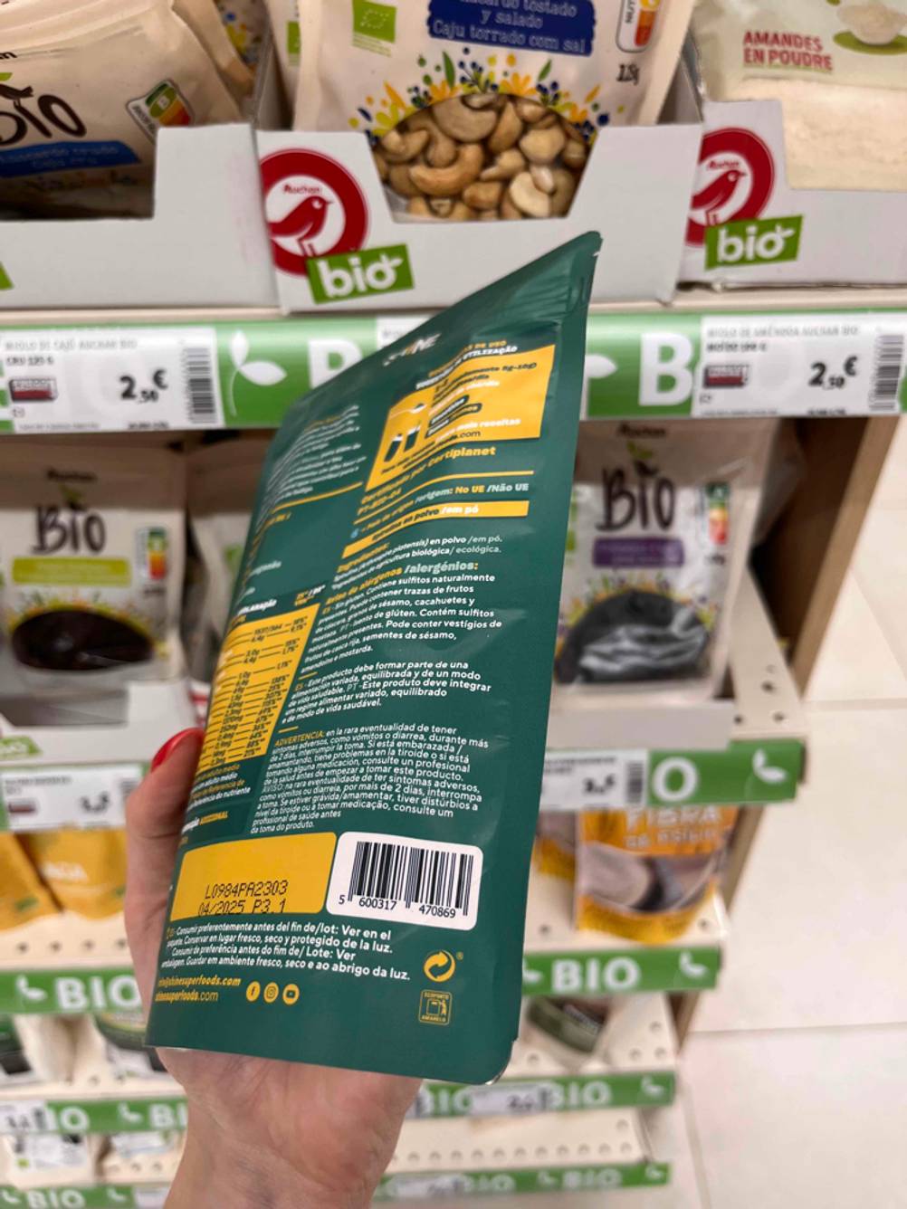 Getestet: Eine Hand hält eine Packung Spirulina-Pulver seitlich, Barcode in Nahaufnahme.
