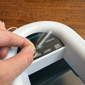 Eine Hand zieht eine Folie vom Shoefresh-Opod-Schuhtrockner ab