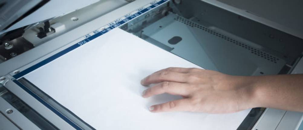 Hand platziert Papier auf einem Test-Dokumentenscanner.