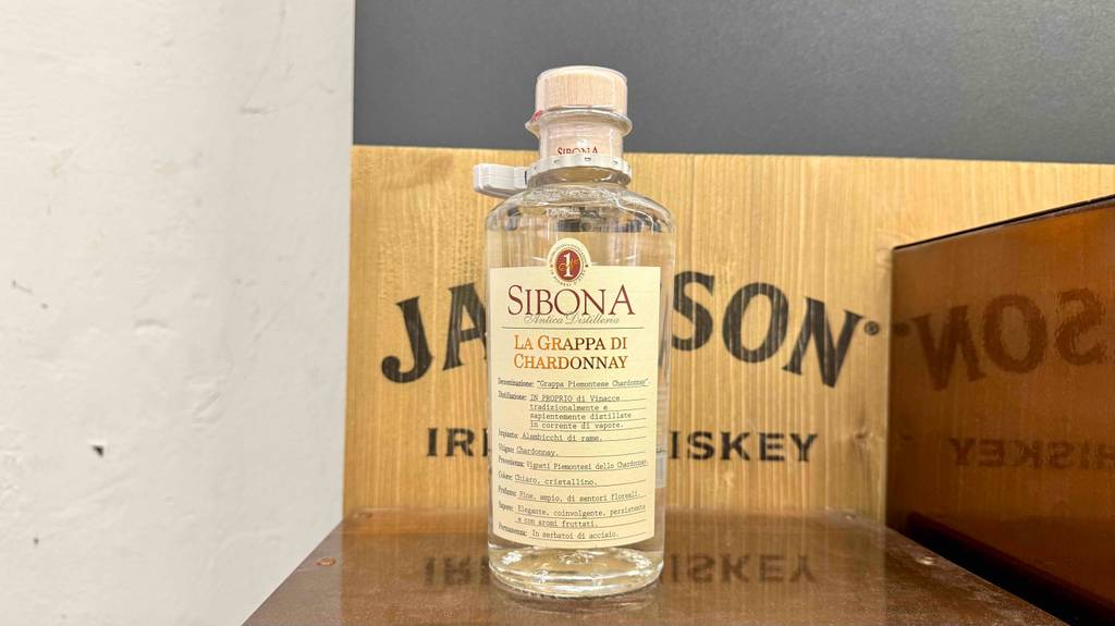 Im Test: Chardonnay Grappa in der Flasche mit Holzkorken steht auf einem Ausstellungsregal.