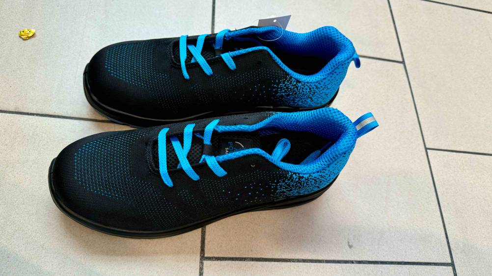 Ein Paar Sicherheitsschuhe-S1 Herren im Test von schräg seitlich auf einem Fließenboden.